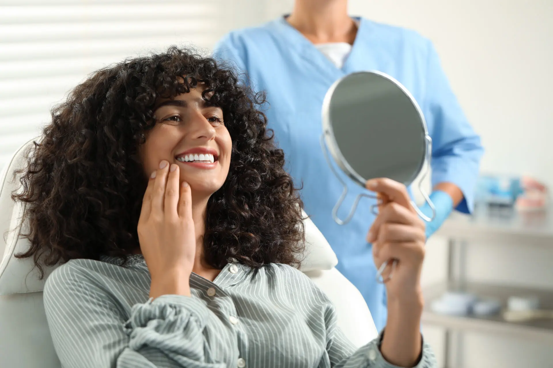 Patient looking in mirror and doctor in clinic, cosmetic dentistry results