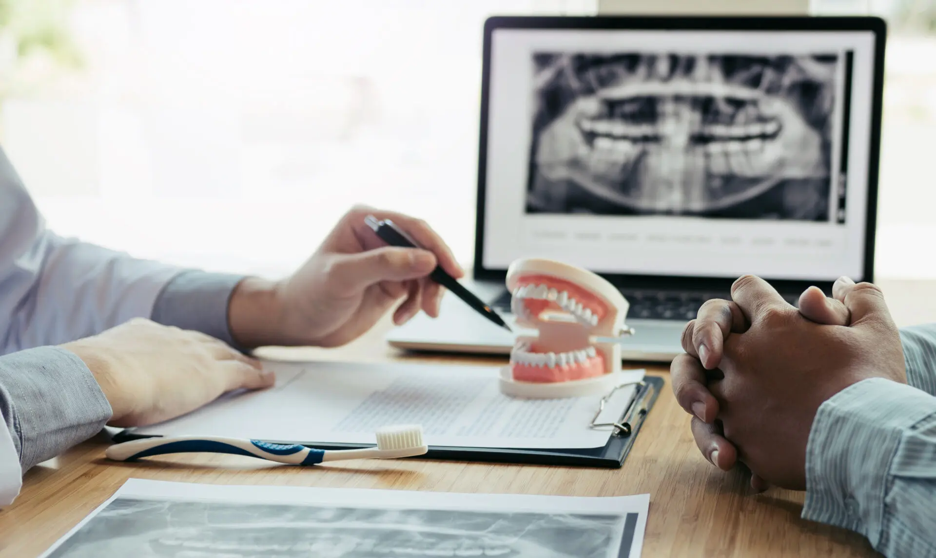 Dentist explaining dental implant treatment using X-rays and a tooth model in Ottawa clinic