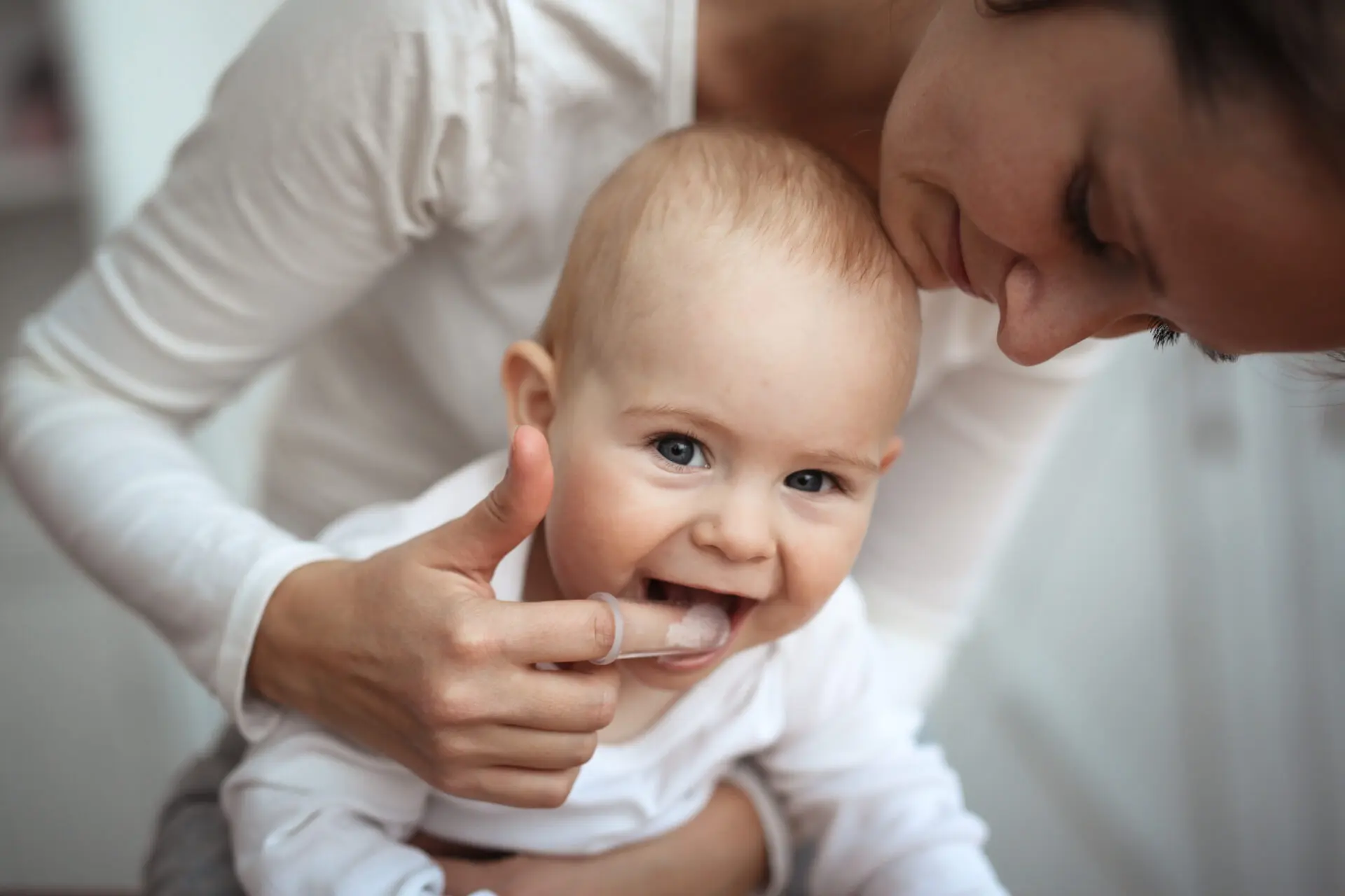 Mom helps to brush teeth of happy baby, Hygiene