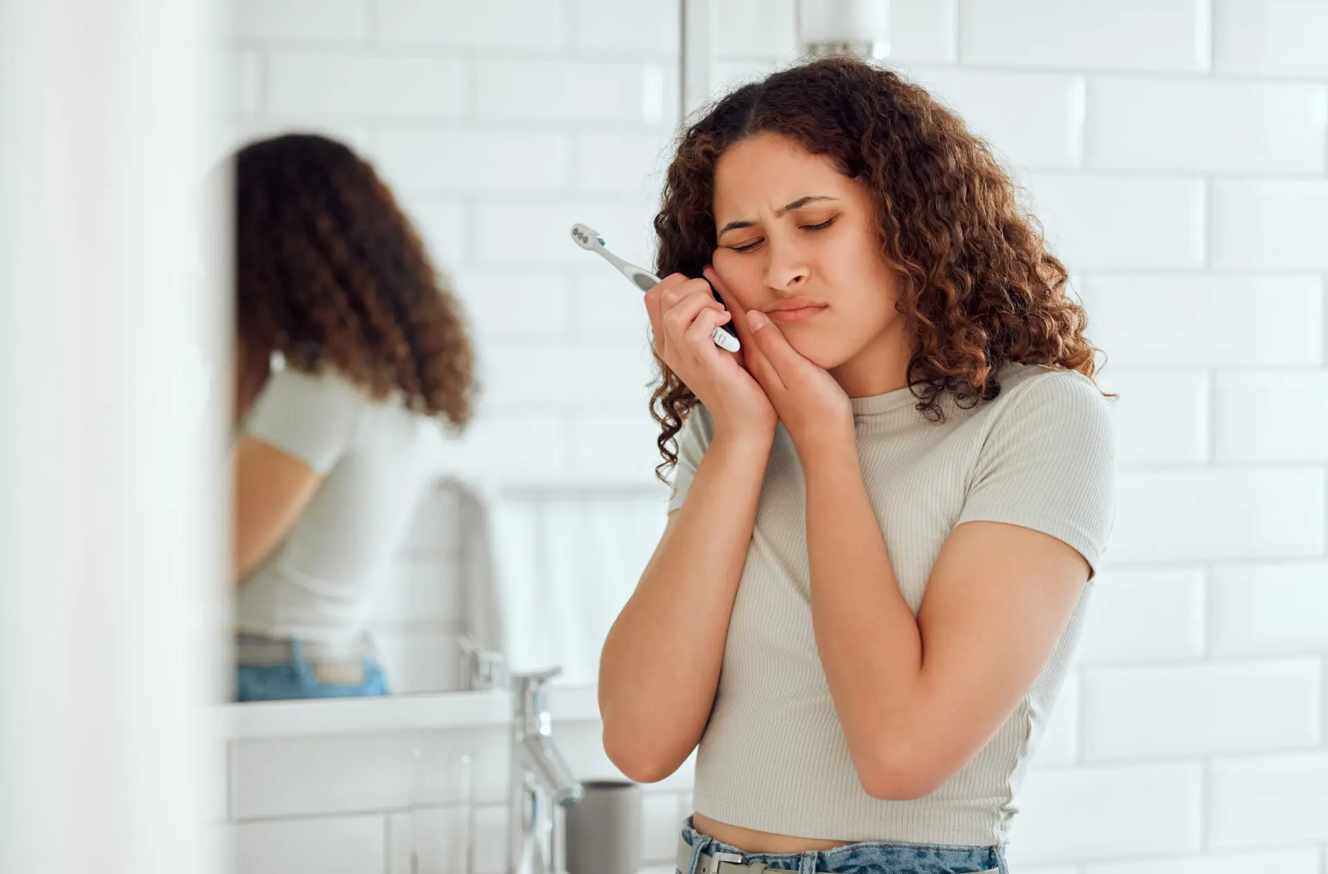 Young female with a cavity suffering from discomfort during dental hygiene routine.