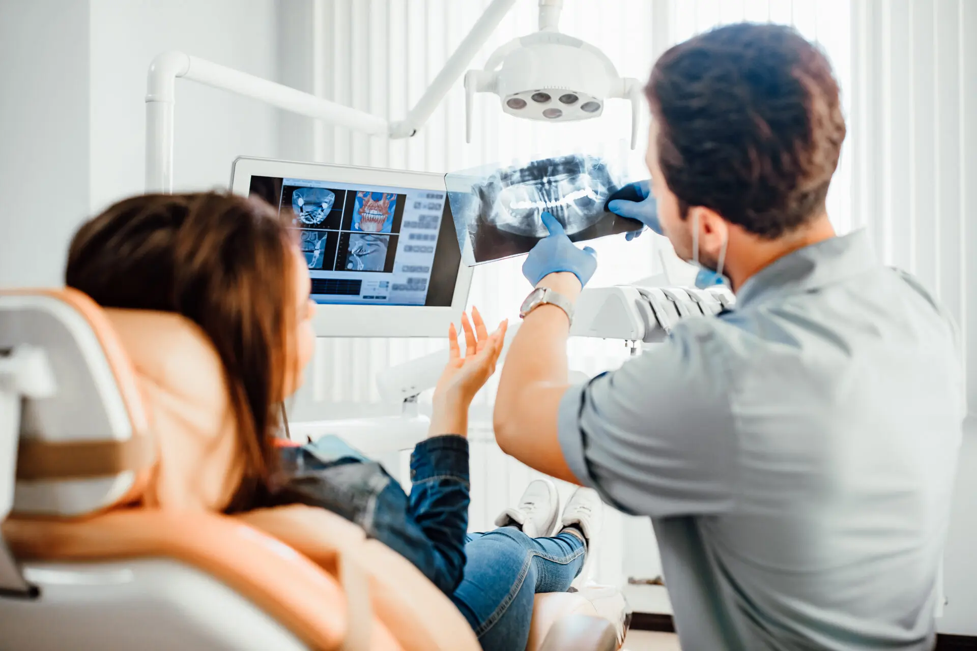 Male dentist showing teeth x-ray to female patient at dental clinic office for the tips for Maximizing Your Benefits section