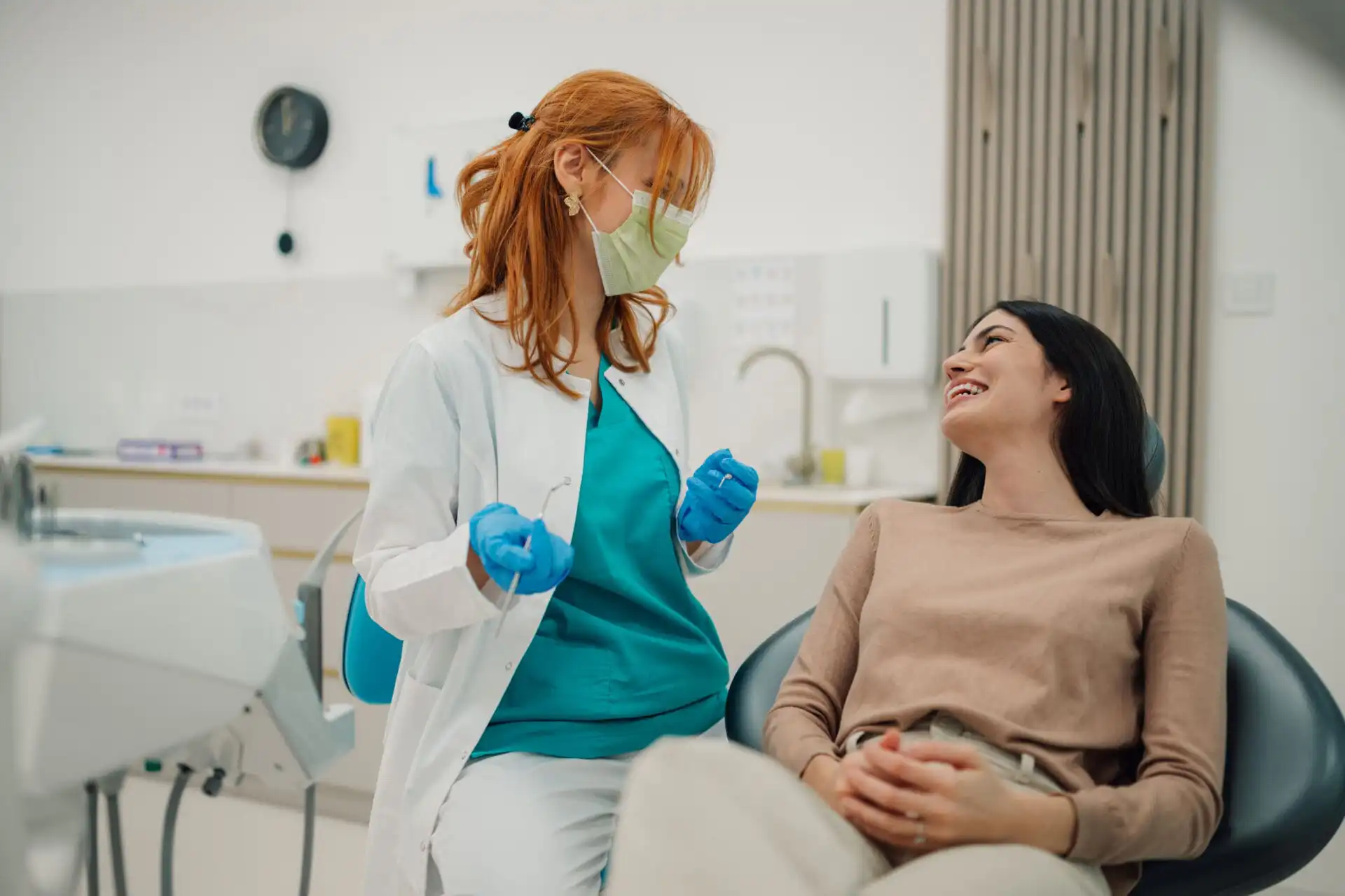 Female dentist wearing surgical mask talking to patient in dental clinic about Gum Disease and Heart Disease