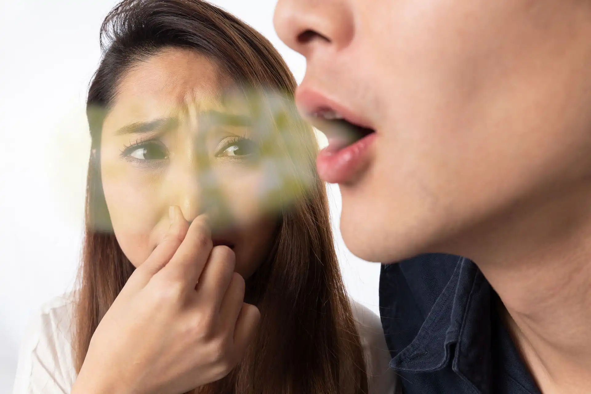 Person reacting to bad breath during conversation, illustrating persistent halitosis
