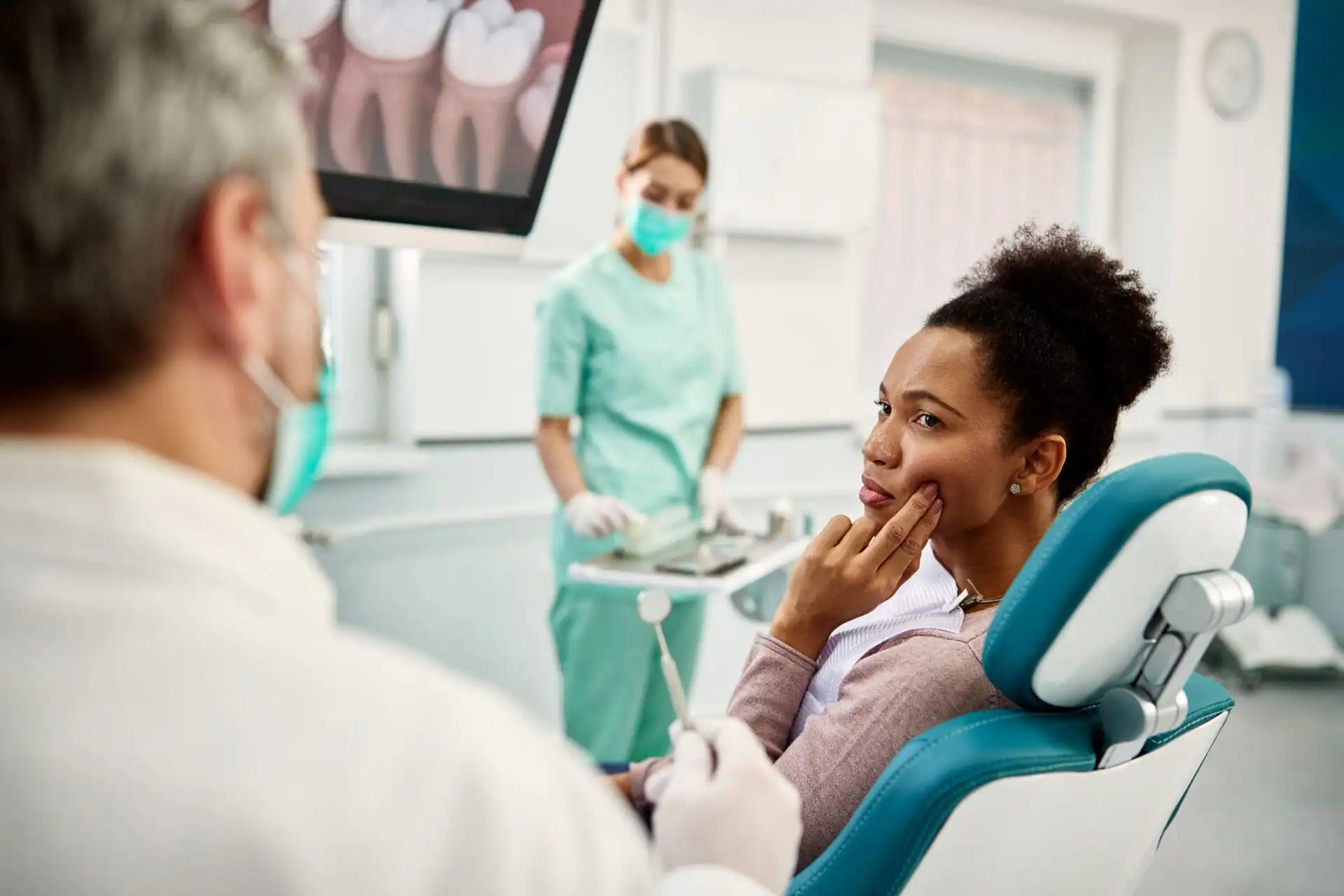Woman complaining of toothache to her dentist during an appointment at a dental clinic.