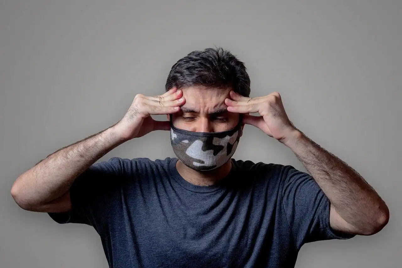 Man touching his forehead in discomfort, showing sinus pressure and headache symptoms often mistaken for tooth pain during cold weather.